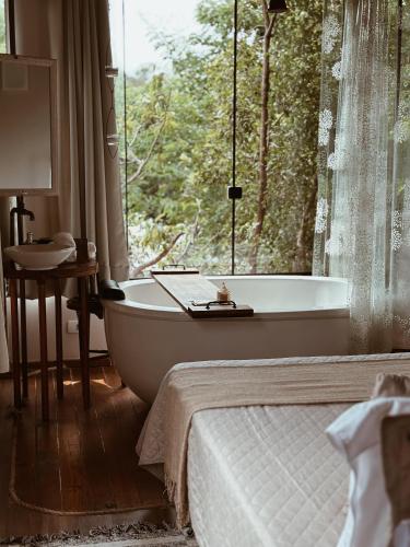a bedroom with a bath tub in front of a window at Vila Abaton in Alto Paraíso de Goiás