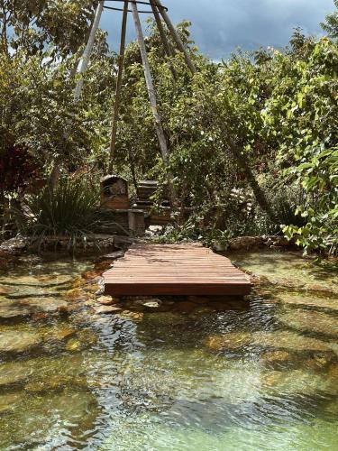 a wooden bridge in the water with a swing at Vila Abaton in Alto Paraíso de Goiás