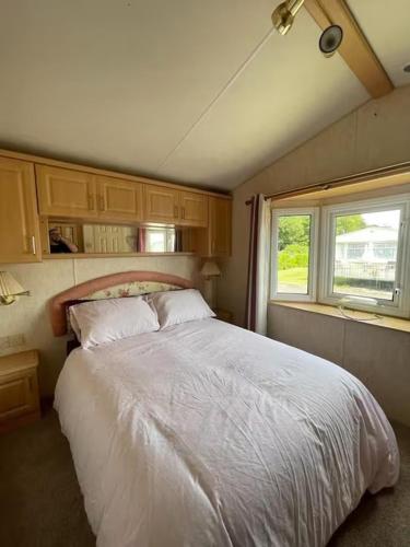 a bedroom with a large white bed with two windows at 6 Berth Caravan Skegness Highfields and the Haven in Winthorpe
