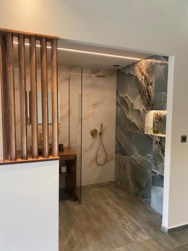 a bathroom with a walk in shower next to a stone wall at Rokamare Beach Resort in Liapades