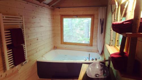 Cette chambre en bois dispose d'une baignoire et d'une fenêtre. dans l'établissement Cabanes des Pins Sylvestres Gélas, à Saint-Martin-Vésubie