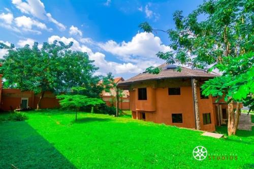a house with a green lawn in front of a building at Trois Ore Residences & Green Earth Bistro in Ibadan