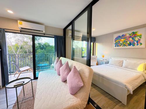 a bedroom with a large bed with pink pillows at Digital Nomad Home Away With Pool & Gym in Nai Yang Beach