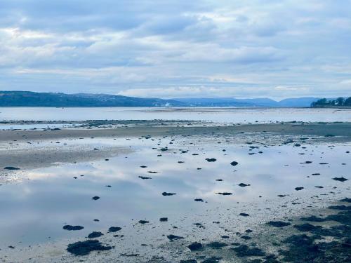 a beach with a reflection of the sky in the water at Flat for 6 guests near Glasgow, Loch Lomond in Dumbarton