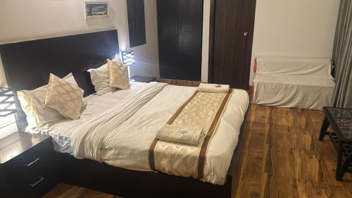a bedroom with a large bed with a bench on it at Garnet suites at omaxe enternity in Chhatikara