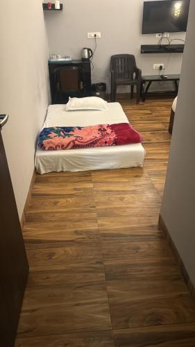 a bedroom with two beds and a wooden floor at Garnet suites at omaxe enternity in Chhatikara