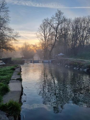 a river in the early morning with the sun rising at Le Moulin de Vilaine in Châteauroux