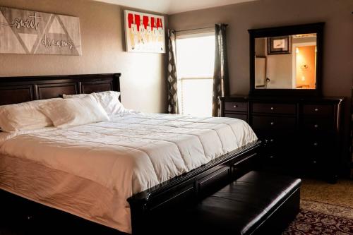 a bedroom with a bed and a dresser and a mirror at Luxury 4br home, 2 king,1 queen, 3bed, 4tv in Wichita Falls