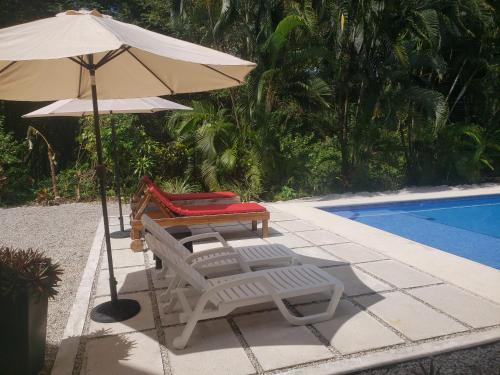 two lounge chairs and an umbrella next to a swimming pool at Casa Vistas del Rio in Sámara