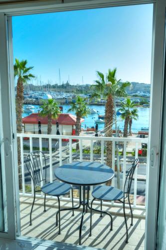 a table and chairs on a balcony with a view of the water at Seafront 2 bedroom with balcony & jacuzzi GOGZR-6 in Il-Gżira