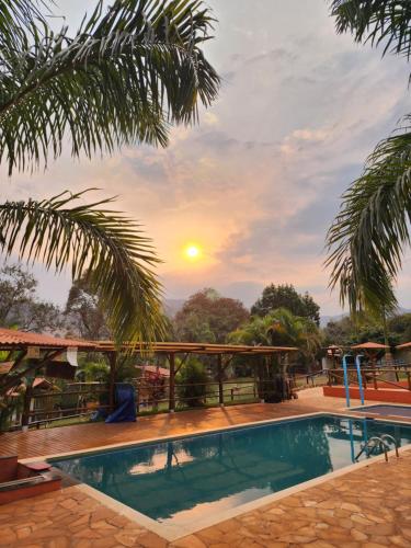 ein Resortpool mit Sonnenuntergang im Hintergrund in der Unterkunft Cabana Hostel Eco Park in São Pedro