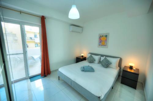 a bedroom with a bed and a large window at Seafront 2 bedroom with balcony & jacuzzi GOGZR-6 in Il-Gżira