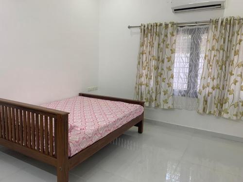 a bedroom with a wooden bed with a pink mattress at The White House in Thodupuzha