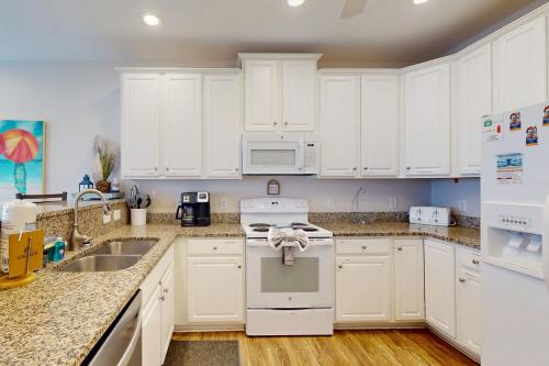 a kitchen with white cabinets and a sink at Shore is Something in North Topsail Beach