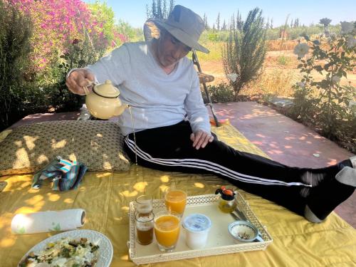 a woman sitting on a table with a tea pot at Gite & Camping route Ouarzazate in Chouiter