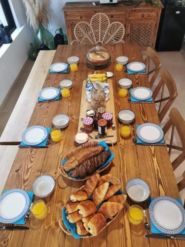 een houten tafel met brood en glazen sinaasappelsap bij Le mas Louga in Flayosc