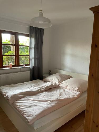 an unmade bed in a bedroom with two windows at Stilvolle 3 Zimmer-Wohnung auf saniertem Resthof in Reher