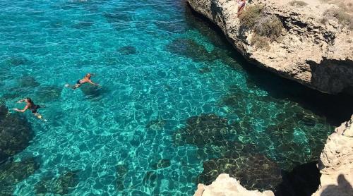 two people swimming in the water near some rocks at Il Gelso in Lecce