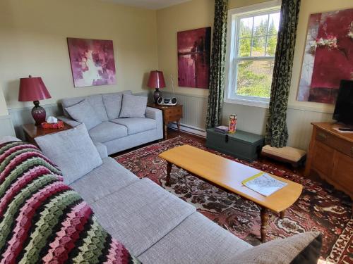 a living room with a couch and a table at Skerwink Trail House in Port Rexton