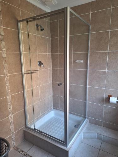 a shower with a glass door in a bathroom at Caribbean Estate Guest House B11 in Port Edward