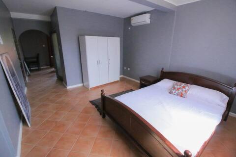 a bedroom with a bed with white sheets and a room with a door at Casa Bonita in Ablekuma