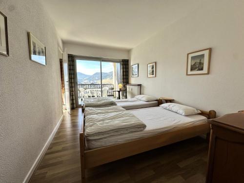 deux lits dans une chambre avec une grande fenêtre dans l'établissement Résidence Le Furon - Spacieux 2 pièces MAE-2354, à Villard-de-Lans