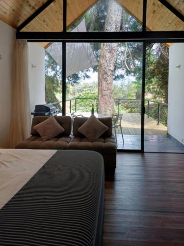 a living room with a couch and a large window at Tree House, Cabaña privada con Jacuzzi in Guatapé