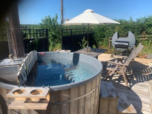 a hot tub sitting on a deck with an umbrella at Stable End in Liskeard
