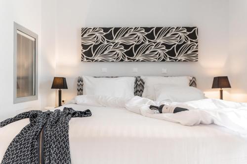 a white bed with a black and white painting on the wall at Galaxy Hotel Naxos in Naxos Chora