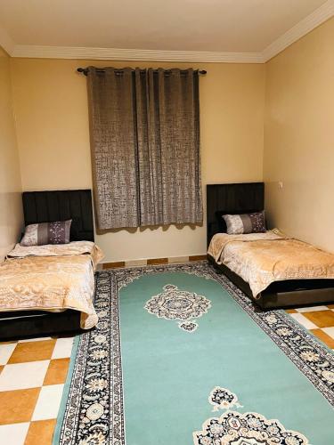 a room with two beds and a large rug at Aéroport, Appartement in Marrakech