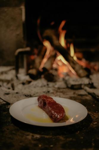 a piece of meat on a plate in front of a fire at Rooms Konoba Pjero in Buje