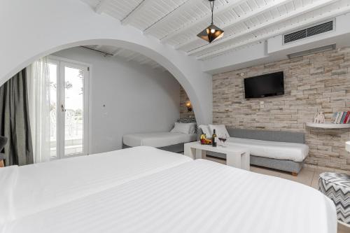 a bedroom with a white bed and a brick wall at Galaxy Hotel Naxos in Naxos Chora