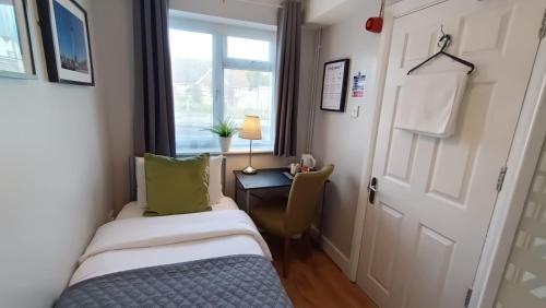 a room with two beds and a desk and a window at Stansted Lodge Elsenham in Elsenham