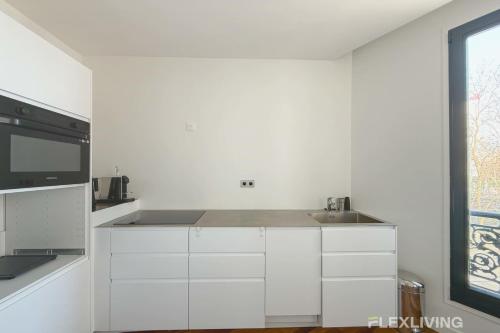 une cuisine blanche avec un évier et un micro-ondes dans l'établissement Superb spacious apartment located at Mont Cenis, à Paris