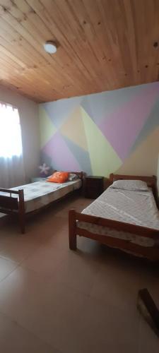 two beds in a room with a colorful wall at El Tropezón in Resistencia
