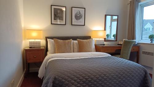 a bedroom with a bed and a desk and two lamps at Stansted Lodge Elsenham in Elsenham