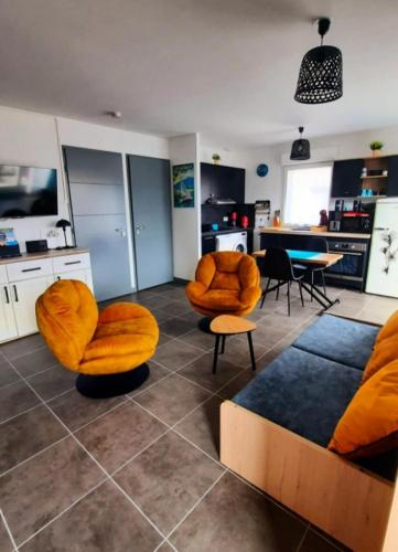 Il comprend un salon doté d'un mobilier orange et d'une cuisine. dans l'établissement Residence Confidence Urbaine - Coup de coeur pour ce joli logement ! MAE-3154, à Aix-les-Bains