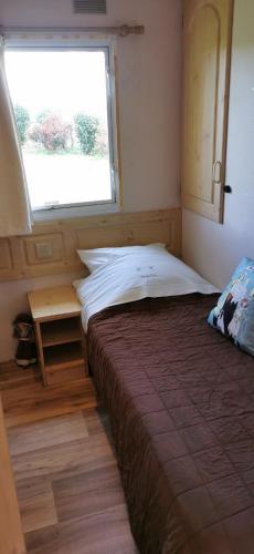 une petite chambre avec un lit et une fenêtre dans l'établissement La Petite Maison dans La Mégie Tiny House, à Troche