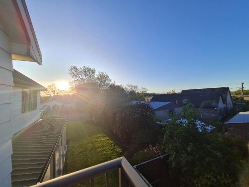 a view of the sunrise from the balcony of a house at Homestay near CHC Airport - 2 rooms in Christchurch
