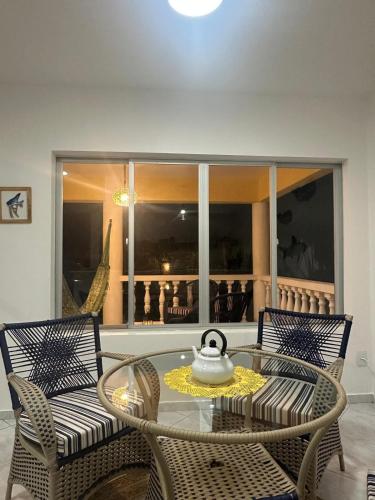 a glass table with two chairs and a tea kettle on it at Beach Life Mirante dos Golfinhos in Nísia Floresta