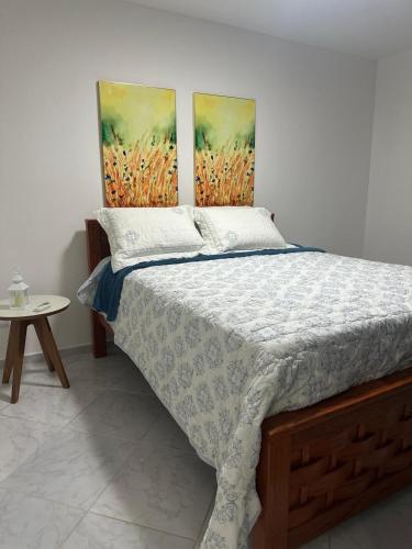 a bedroom with a bed with two paintings on the wall at Beach Life Mirante dos Golfinhos in Nísia Floresta