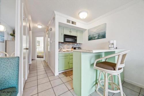 a kitchen with green cabinets and a counter top at Ocean View - Hot Tubs - Heated Pool - Gym - Tennis ct - Shoreline Stays 22 in Galveston