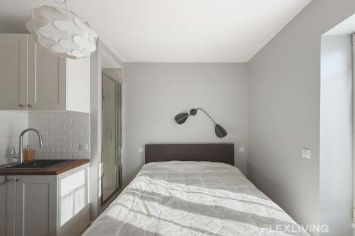 - une chambre blanche avec un lit et une lampe dans l'établissement Chabrol - Beautiful bright and fully equipped T1, à Paris