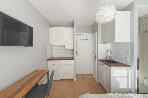 une cuisine avec des armoires blanches et une table en bois dans l'établissement Chabrol - Beautiful bright and fully equipped T1, à Paris