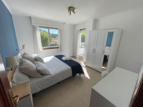 a white bedroom with a bed and a window at Apartamentos Telleira in Nigrán