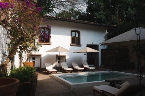a pool with chairs and umbrellas next to a building at Batucada Hotel Boutique in Valle de Bravo