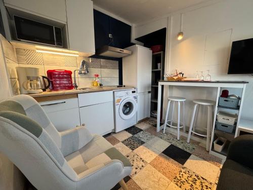 une cuisine avec des armoires blanches et une laveuse et une sécheuse dans l'établissement Meublé Chic AJACQUEE, à Celles-sur-Belle