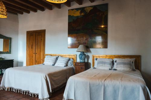 a bedroom with two beds and a painting on the wall at Batucada Hotel Boutique in Valle de Bravo