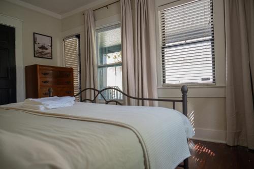 a bedroom with a bed and a dresser and two windows at Historic Orlando Casita Love Apt A with backyard in Orlando