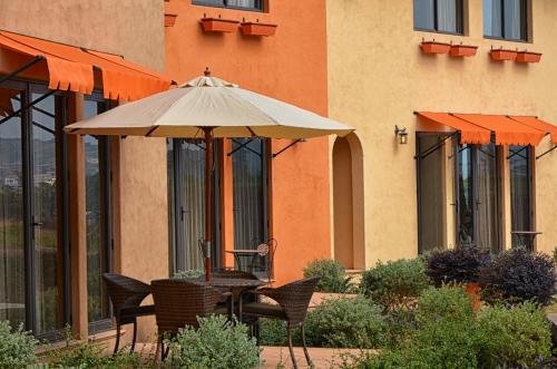 a table and chairs with an umbrella in front of a building at Toscana Hotel La Casetta in Mu Si
